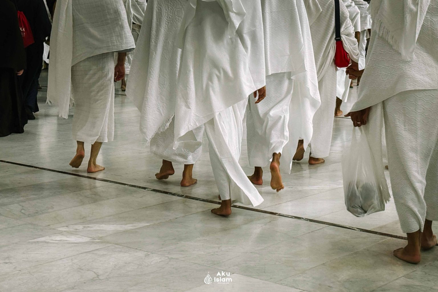 Jemaah berpakaian ihram berjalan tanpa alas kaki di lantai marmar Masjidil Haram