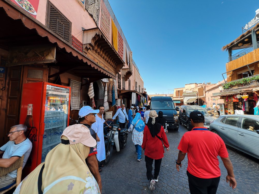 Jalan sibuk dengan kedai dan bangunan merah berhampiran pintu Medina Marrakech