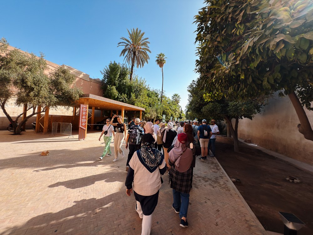 Pelawat berjalan di laluan berpokok palma di dalam Medina Marrakech