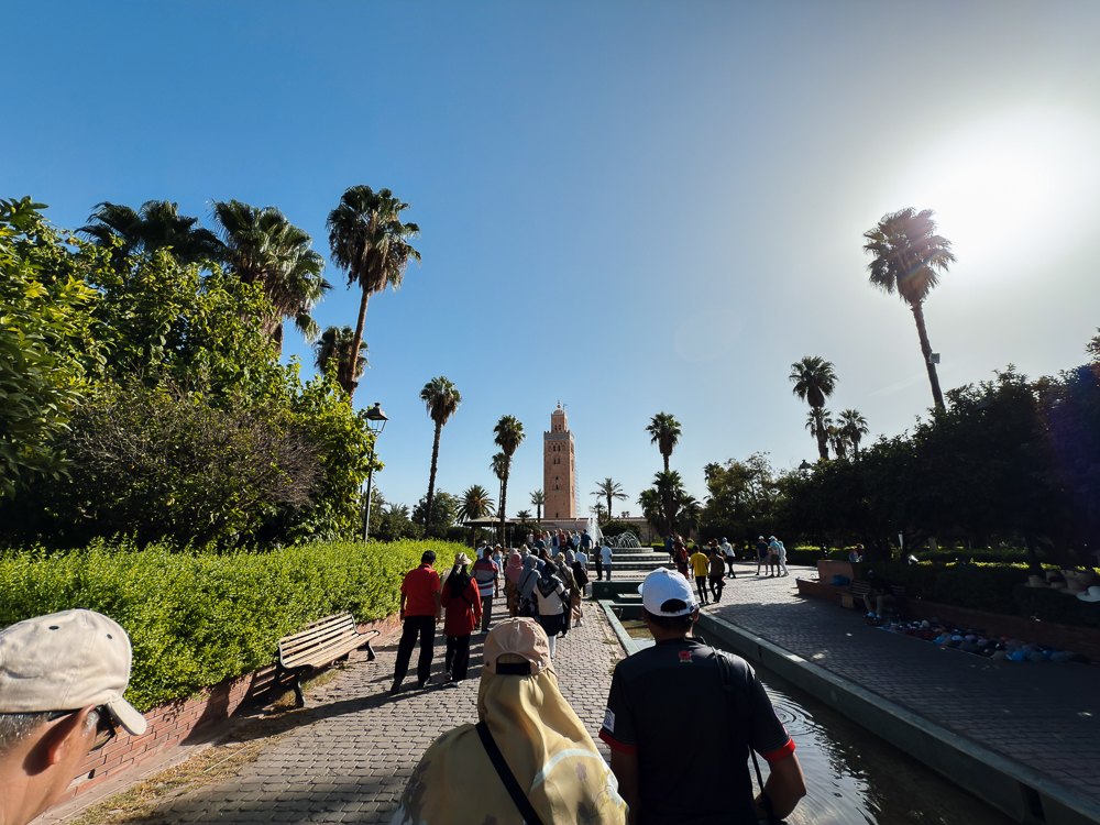 Laluan taman berpalma menuju Masjid Koutoubia Marrakech dengan menaranya di kejauhan