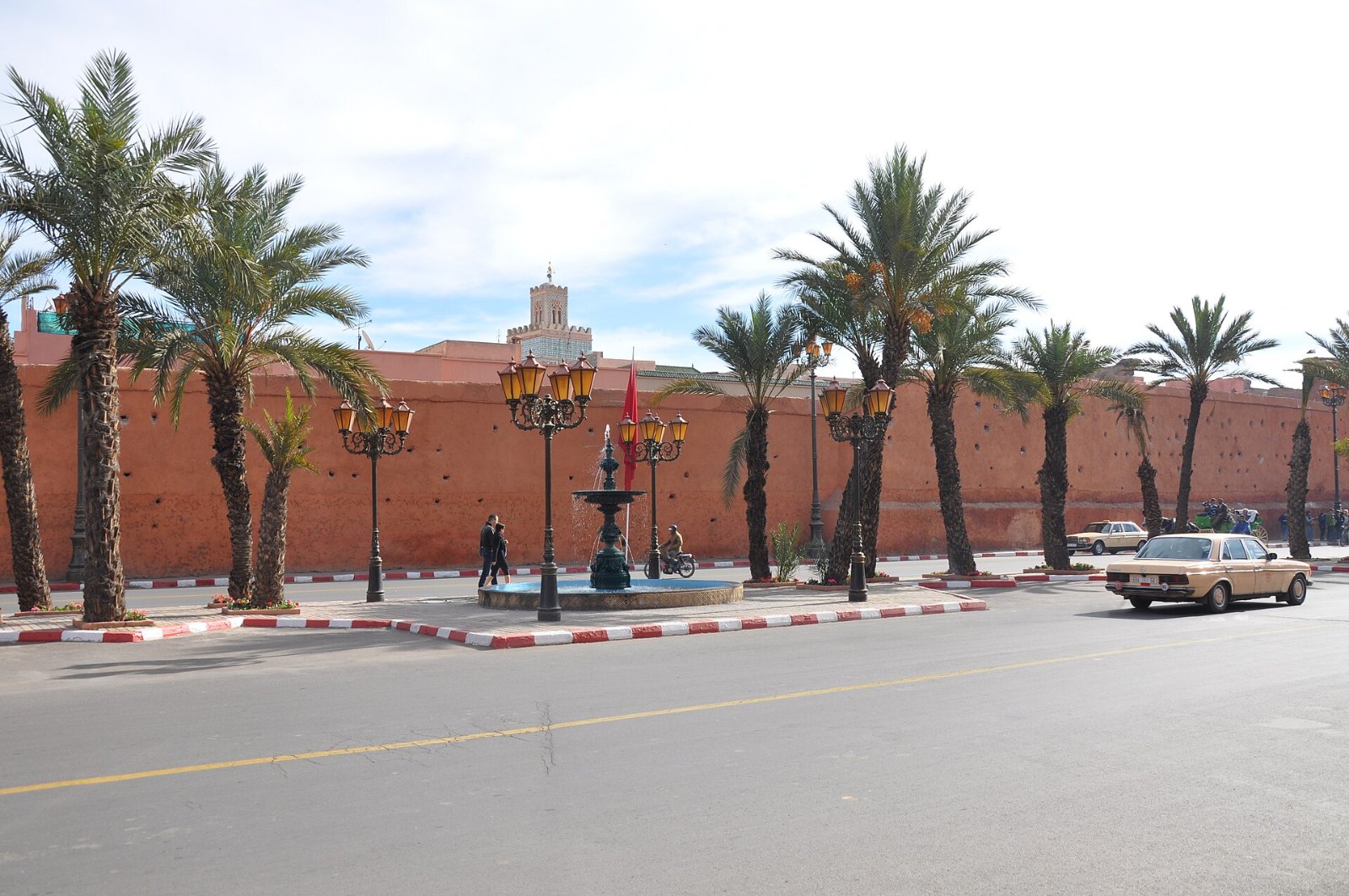 Tembok tanah merah kota lama Marrakech di tepi jalan raya