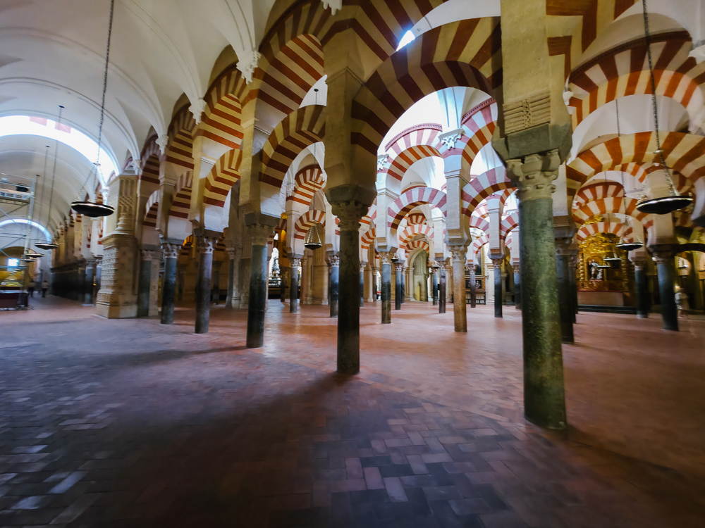 Ruang dalaman Masjid Agung Cordoba dengan tiang dan lengkungan merah putih warisan seni bina Andalusia.