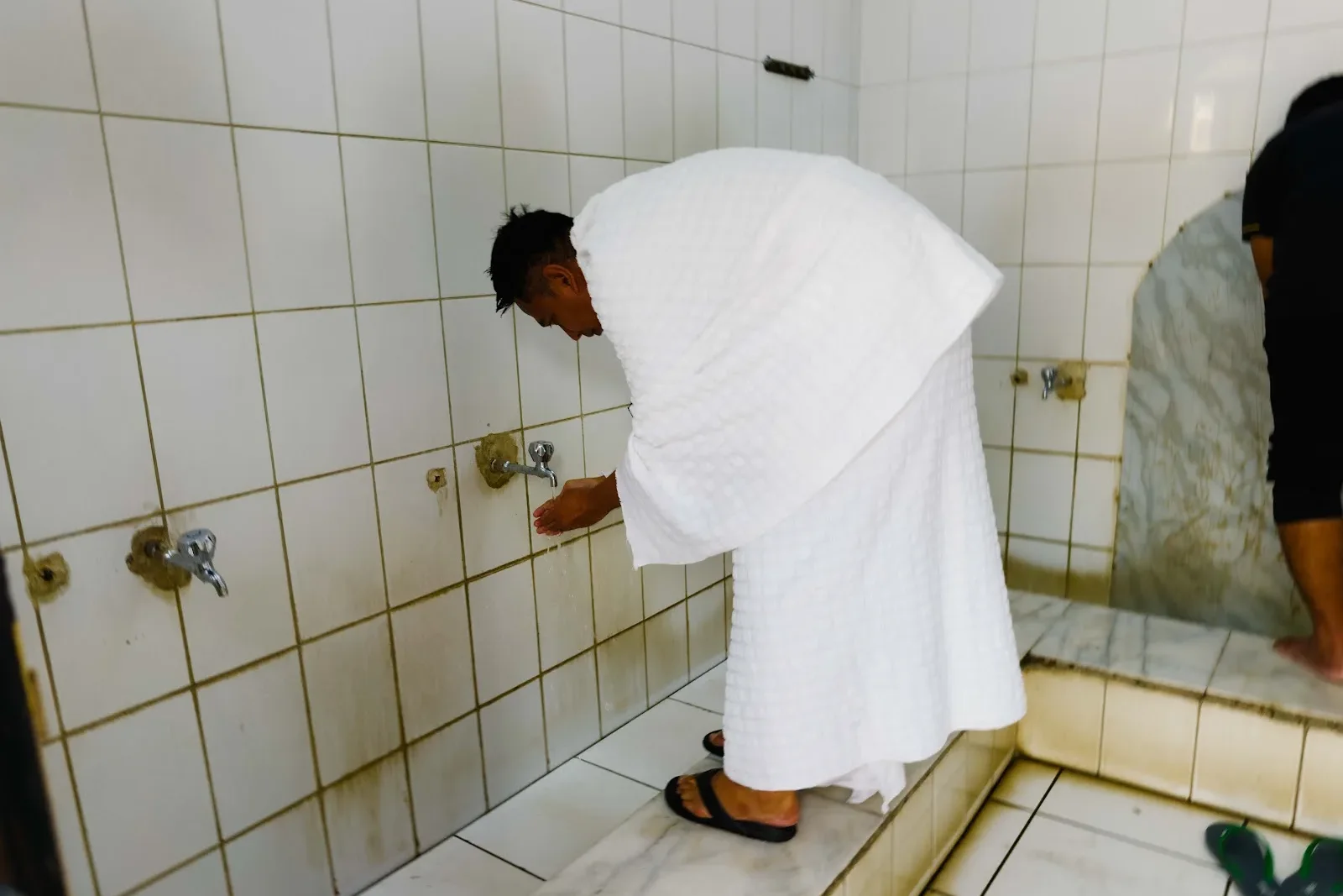 Jemaah lelaki berpakaian ihram mengambil wuduk di tempat wuduk masjid miqat