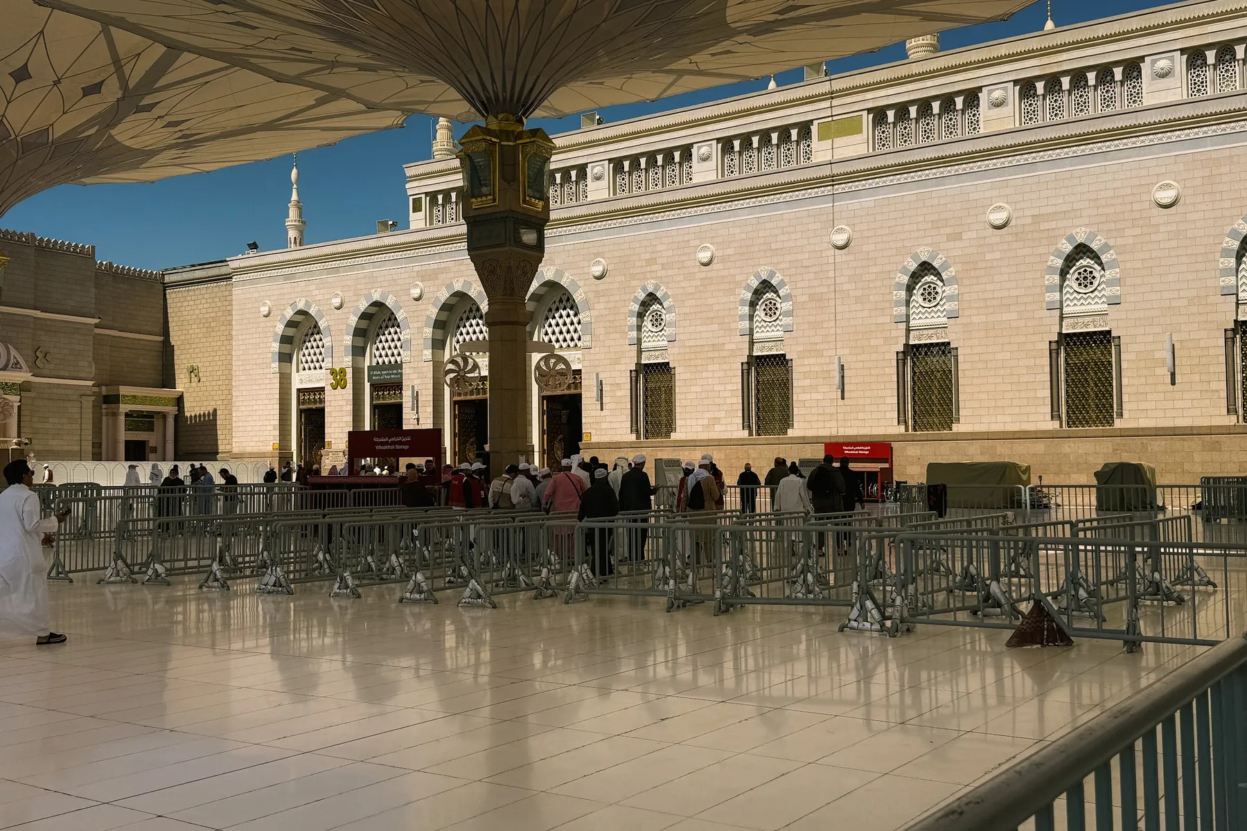 Deretan pintu Masjid Nabawi dan payung gergasi di halaman masjid, Madinah
