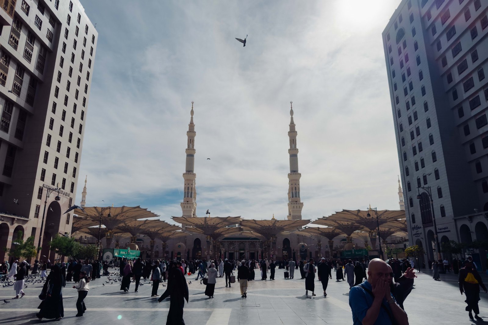 Jemaah berjalan di dataran Masjid Nabawi dengan dua menara di hujung pandangan