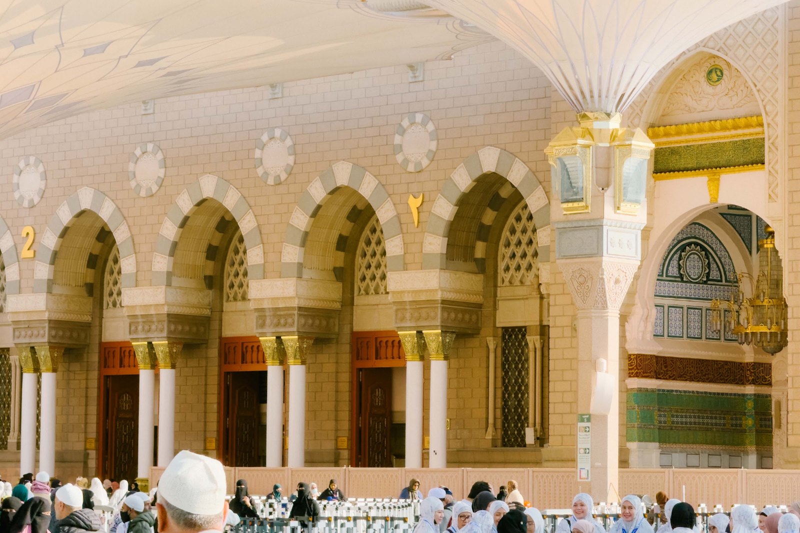 Jemaah di halaman Masjid Nabawi berhampiran gerbang berukir dan payung gergasi