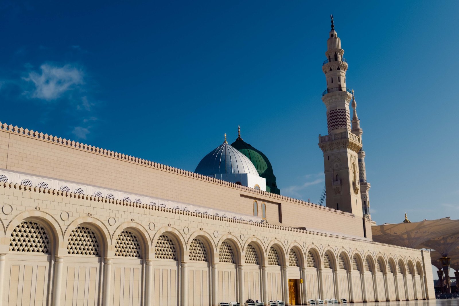 Dinding, kubah hijau dan menara Masjid Nabawi di bawah langit biru Madinah