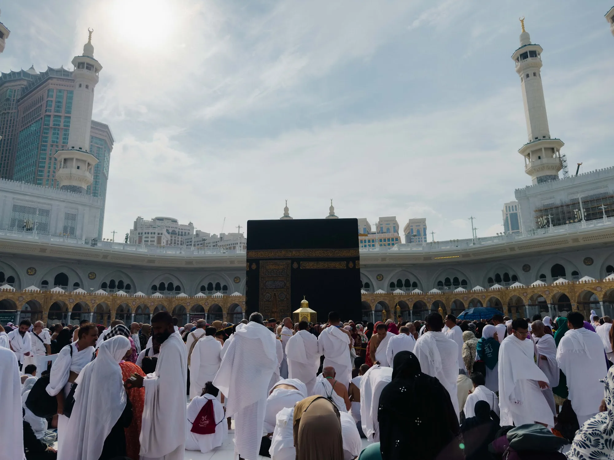 Kaabah dilihat dari dataran tawaf dengan menara Masjidil Haram dan jemaah berpakaian ihram