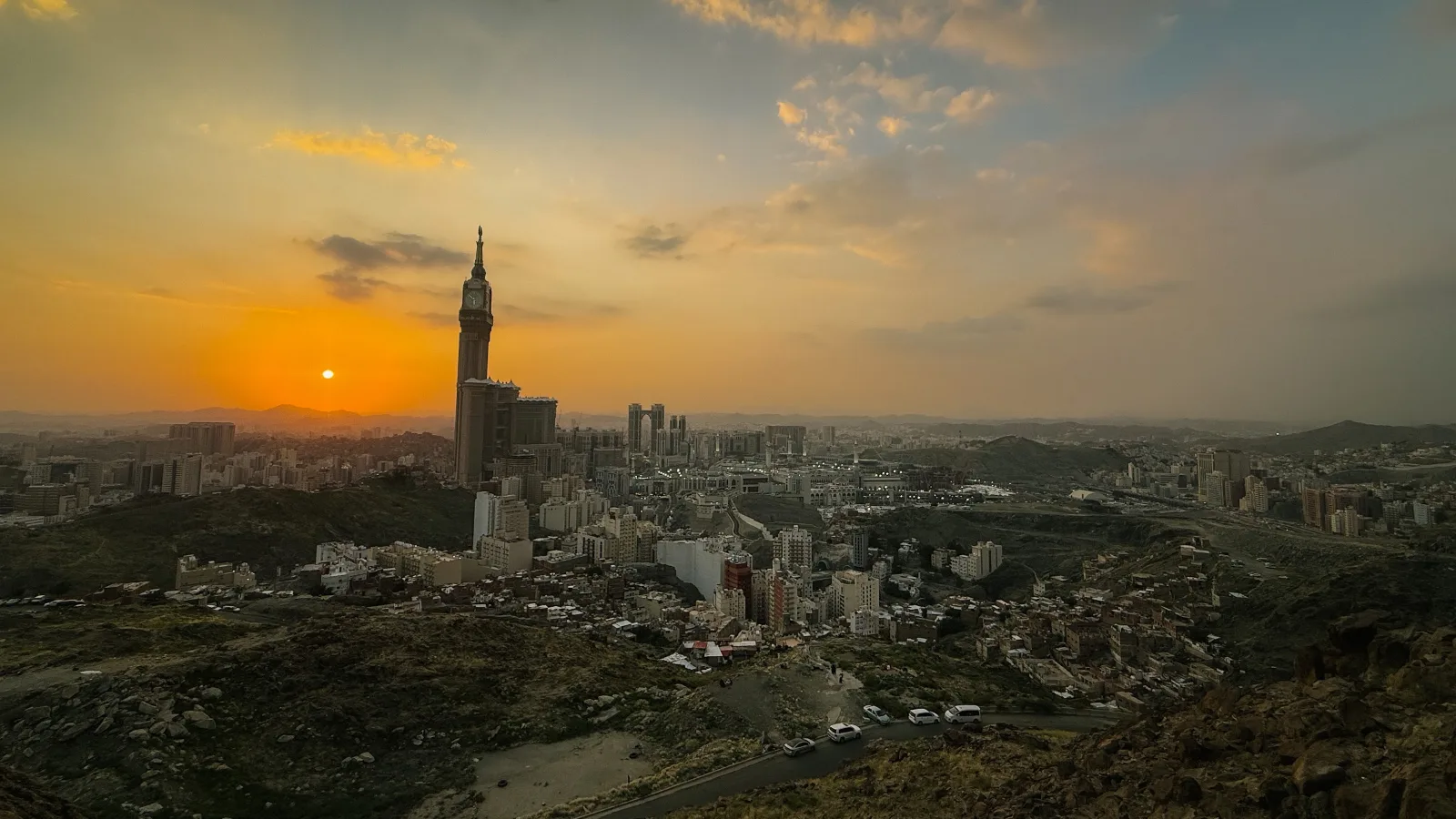 Panorama kota Makkah dari lereng bukit berbatu ketika matahari terbenam