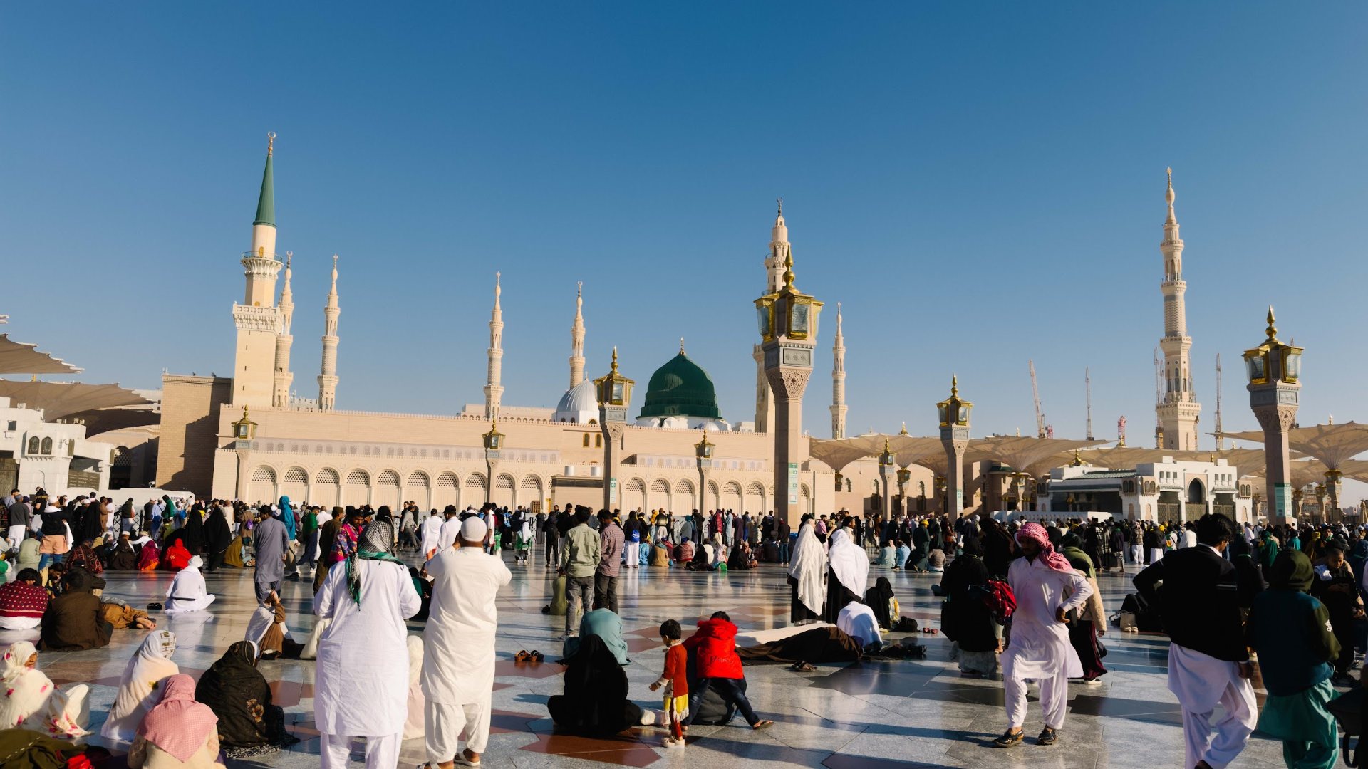 Halaman Masjid Nabawi di Madinah dengan Kubah Hijau dan menara, dipenuhi jemaah