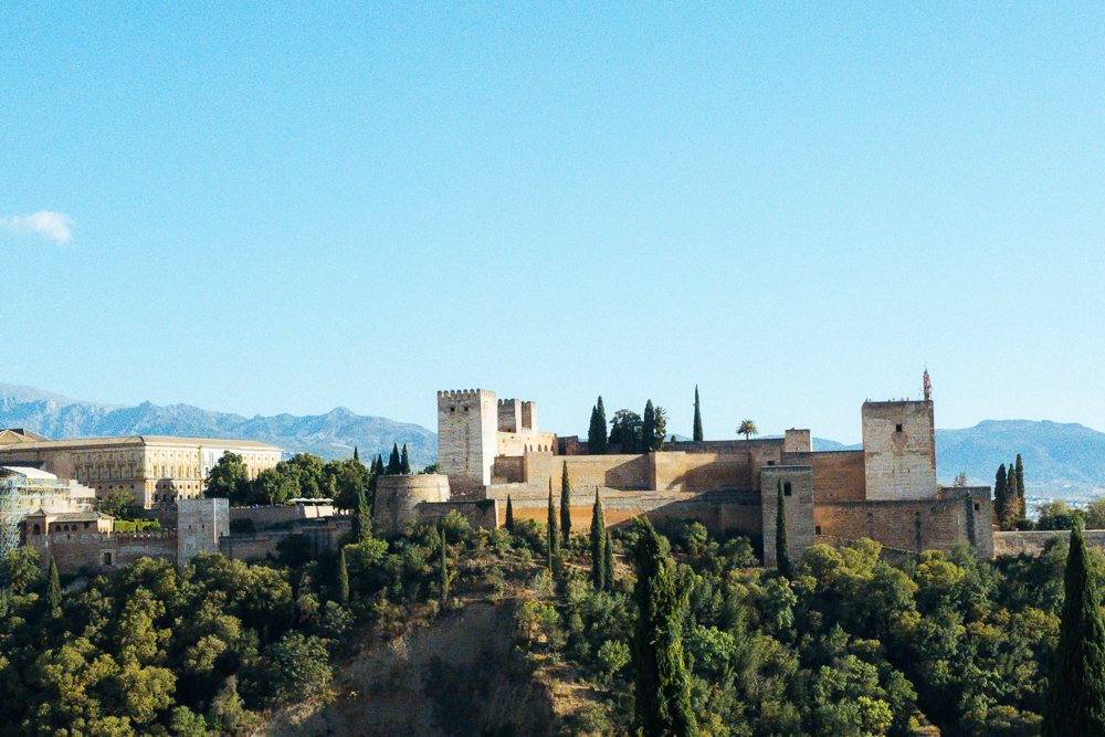 Kubu Alcazaba dan menara Alhambra di atas bukit berhutan, Granada