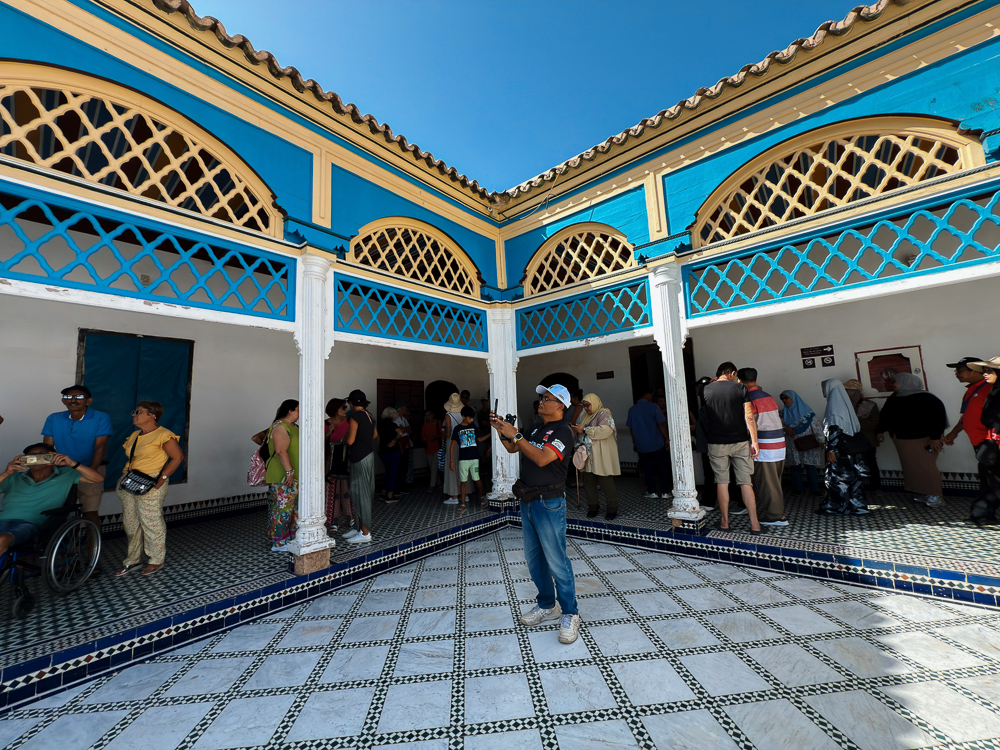 Halaman besar berlantai marmar di Istana Bahia Marrakech dengan pelawat berkerusi roda