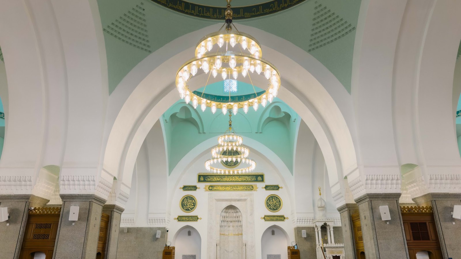 Ruang solat utama Masjid Quba dengan candelier dan mihrab berhias hijau