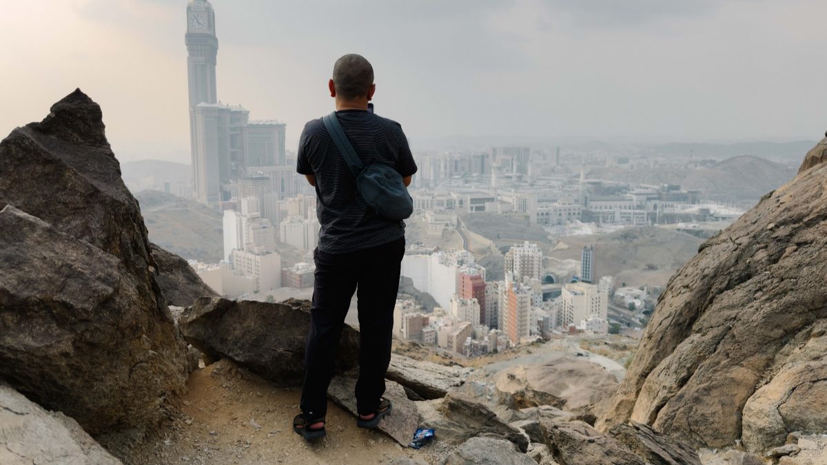 Pengunjung berdiri di celah batu Jabal Khandamah memandang ke arah Masjidil Haram