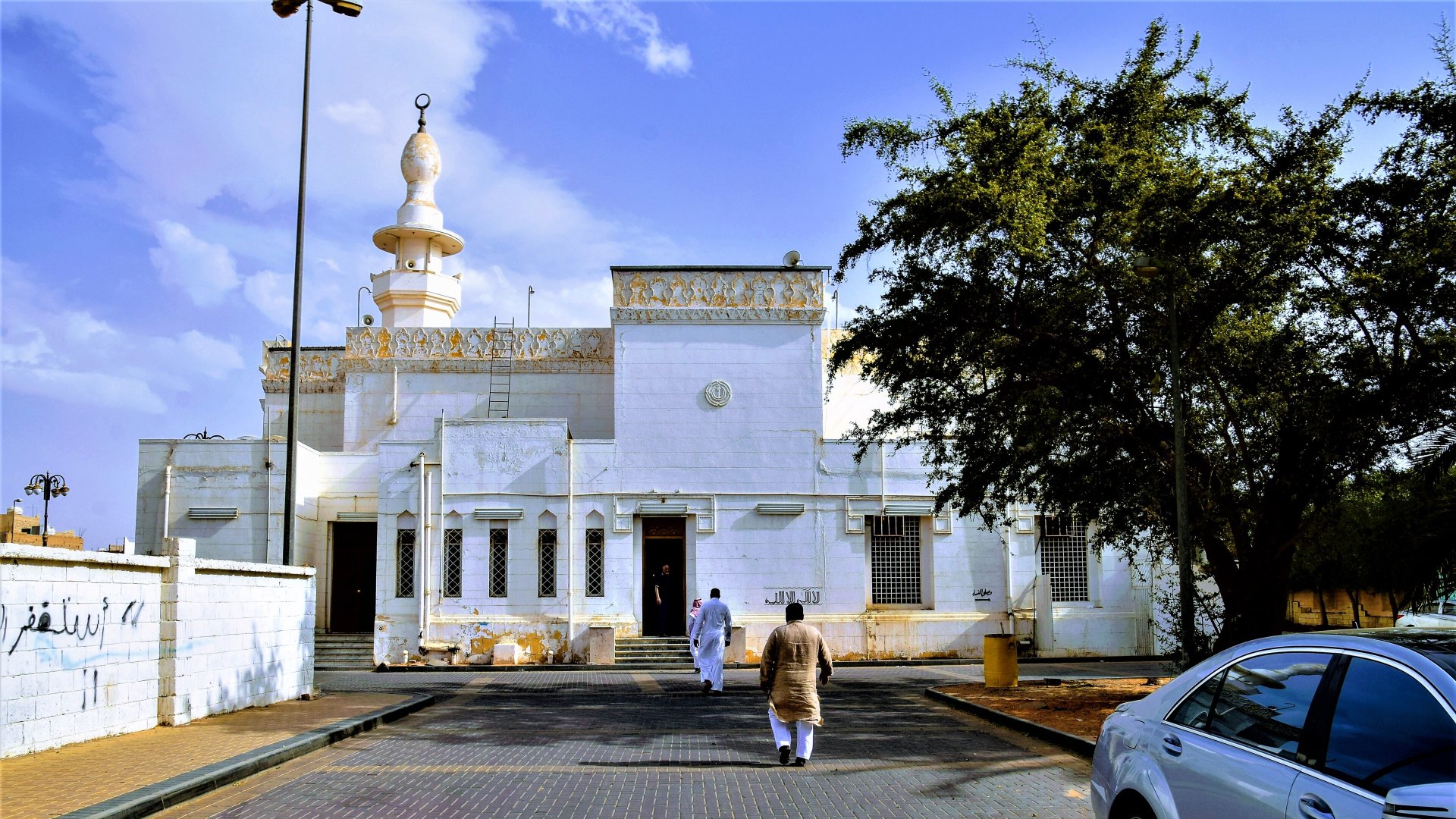 Bangunan putih Masjid at-Taubah di Tabuk dengan menara tunggal dan sebatang pokok di sisi kanan