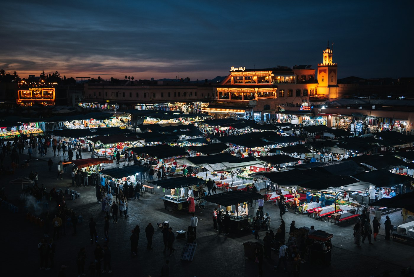 Pemandangan Jemaa el-Fnaa Marrakech pada waktu malam dengan deretan gerai makanan yang bercahaya