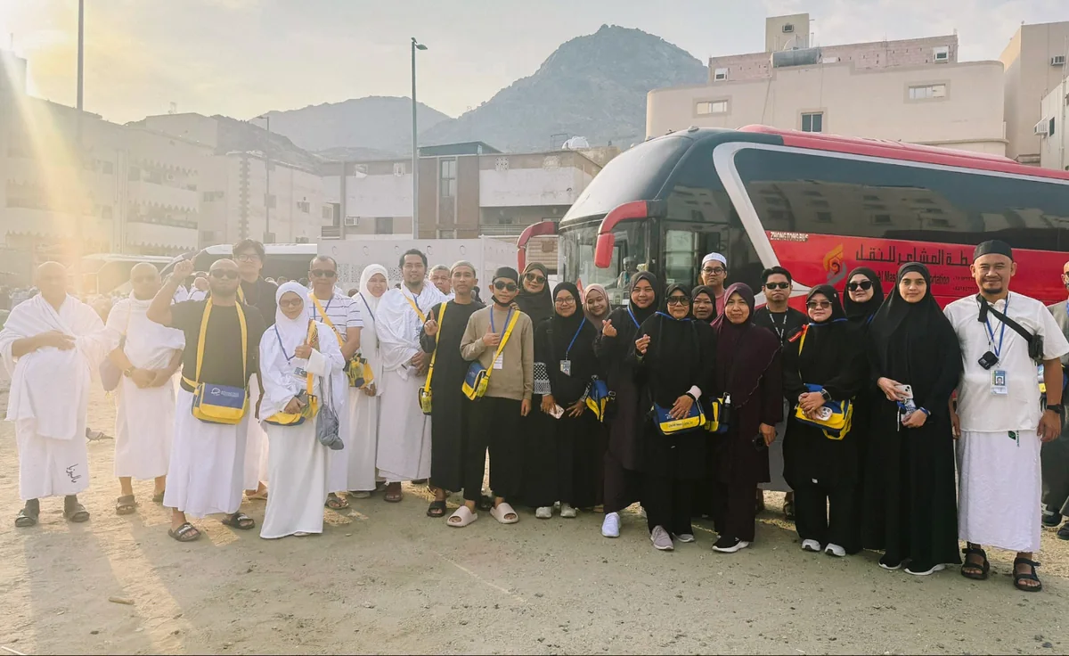 Jemaah umrah rombongan bergambar di hadapan bas di Makkah