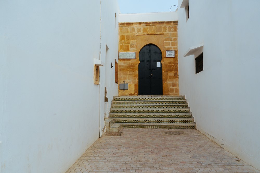 Lorong sempit bertangga menuju pintu kayu di dalam kasbah