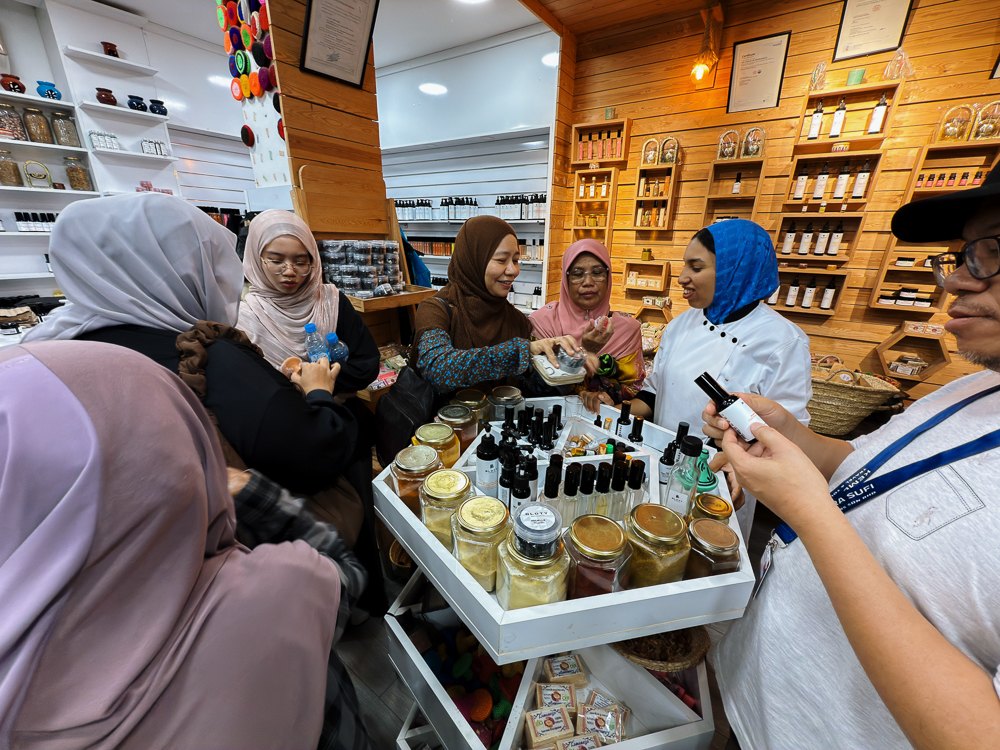 Pelawat mencuba minyak dan krim herba di atas troli kedai herba Marrakech