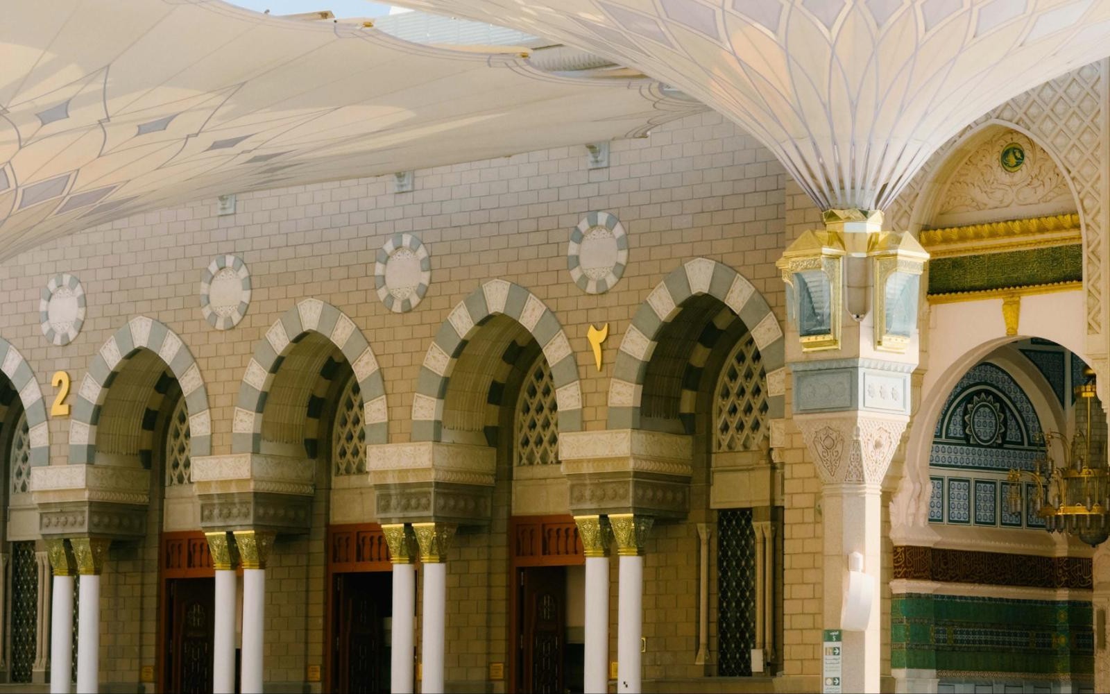 Deretan lengkungan dan pintu Masjid Nabawi di bawah payung gergasi