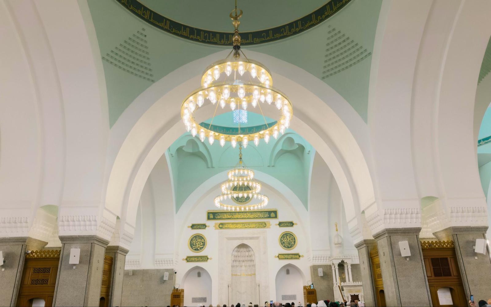 Ruang solat utama Masjid Quba dengan candelier dan mihrab berhias kaligrafi