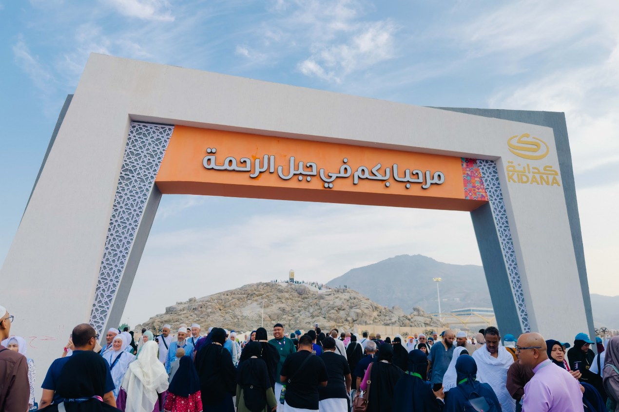 Pintu gerbang Jabal Rahmah dengan tulisan Arab selamat datang dan jemaah di bawahnya