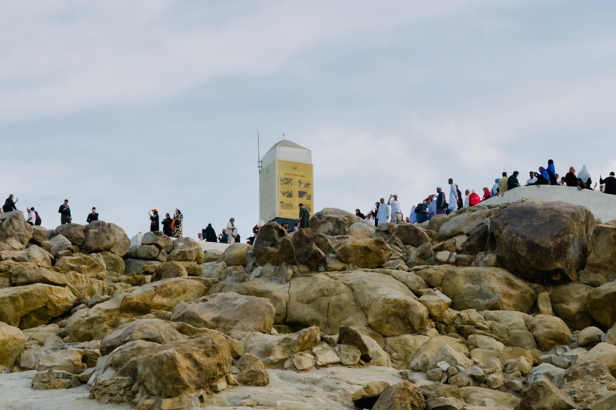 Puncak Jabal Rahmah yang berbatu dengan tiang putih dan pengunjung
