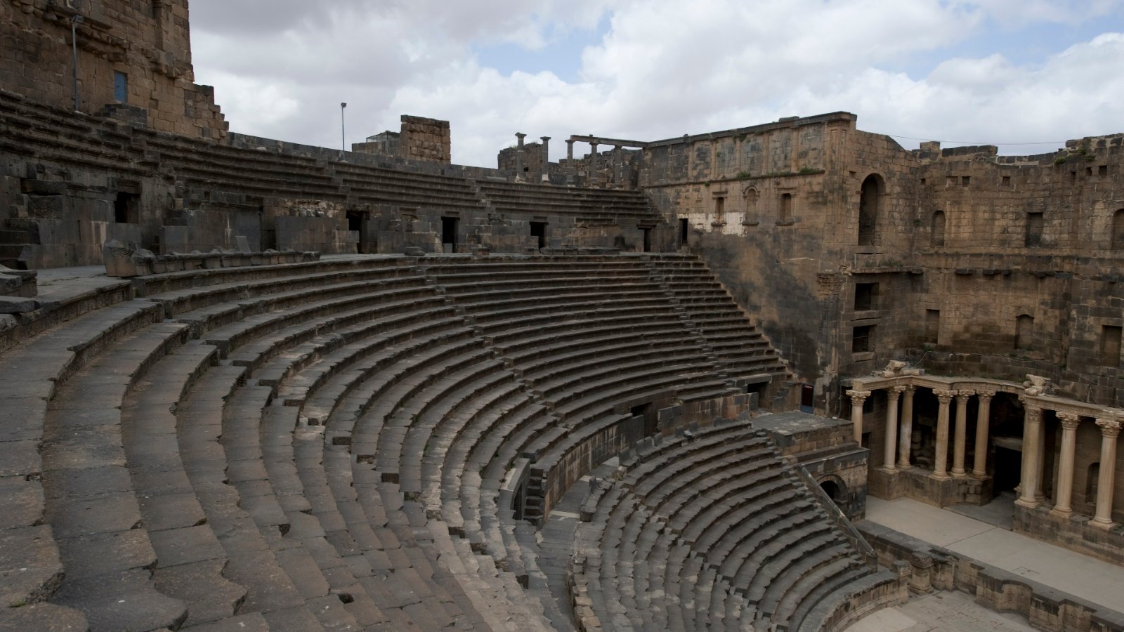 Tempat duduk batu basalt Teater Rom di kota purba Busra, Syria