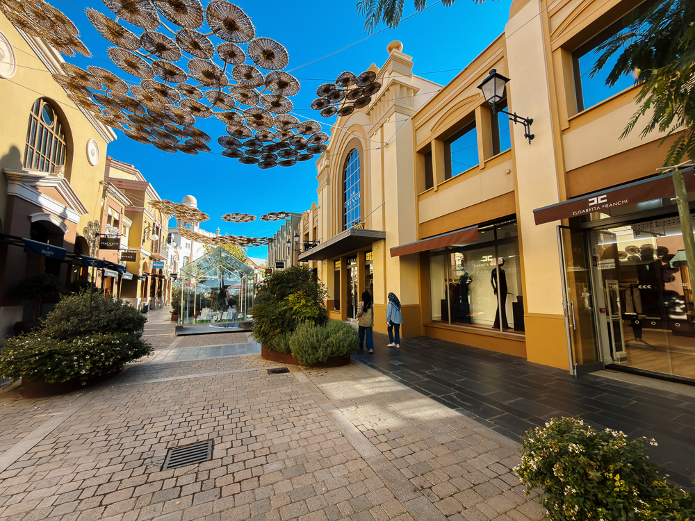 Deretan kedai dan pasu tanaman di lorong Las Rozas Village