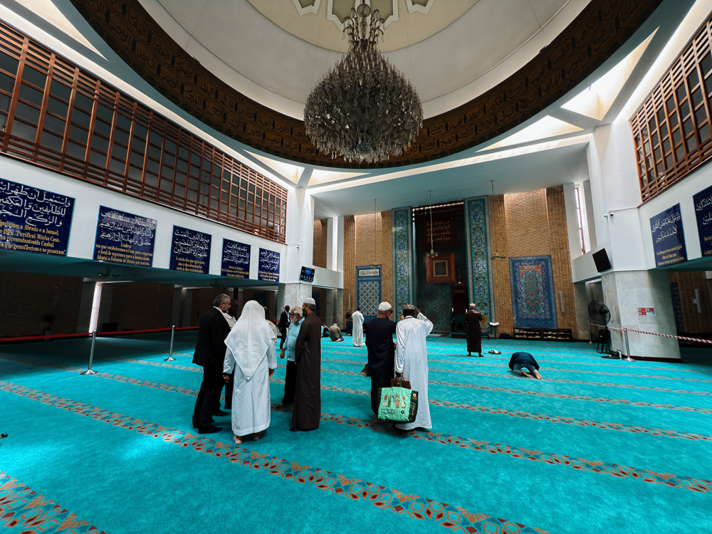 Dewan solat utama Mesquita Central de Lisboa dengan karpet biru dan candelier