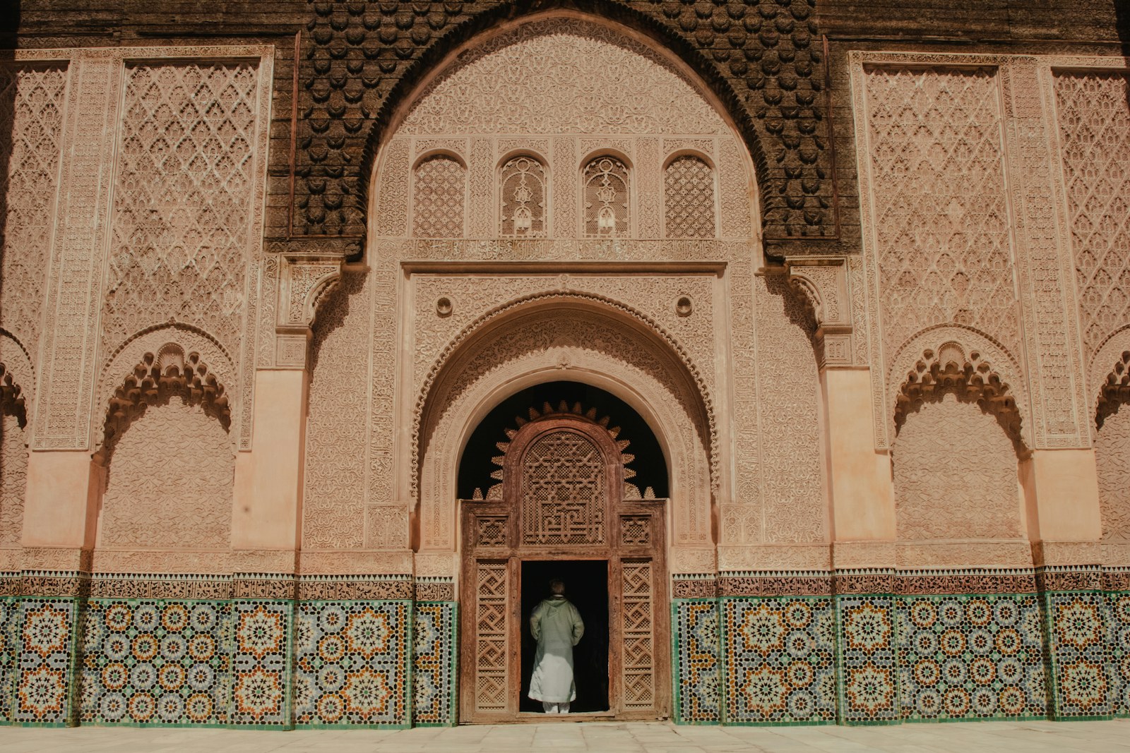 Fasad berukir dan jubin zellige di halaman Madrasah Ben Youssef Marrakech