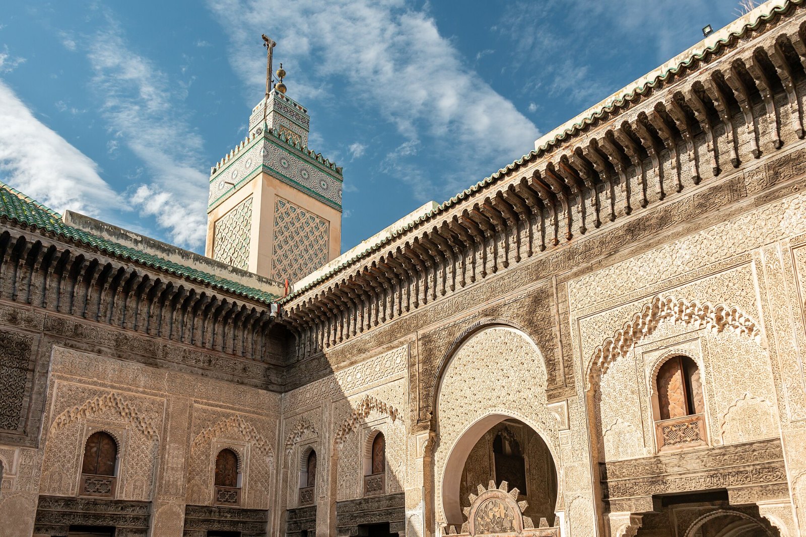 Halaman Madrasah Bou Inania di Fez dengan ukiran kayu dan menara berjubin hijau