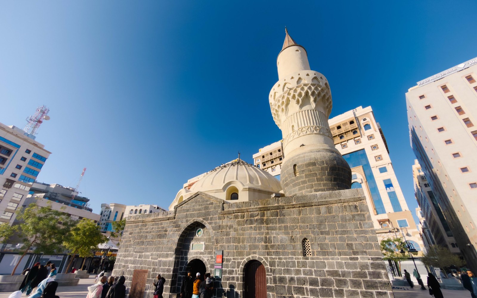 Masjid Abu Bakar al-Siddiq dengan dinding batu basalt hitam, kubah dan menara silinder di kawasan al-Musalla, Madinah