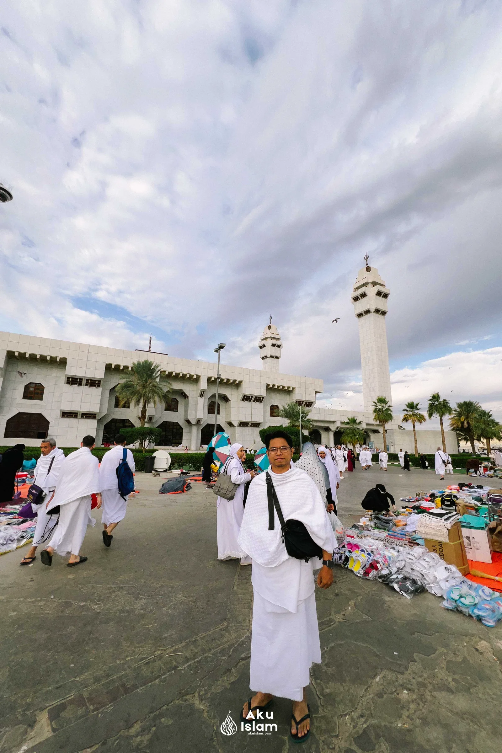Jemaah berihram berjalan di halaman Masjid Aisyah dengan gerai di tepi laluan