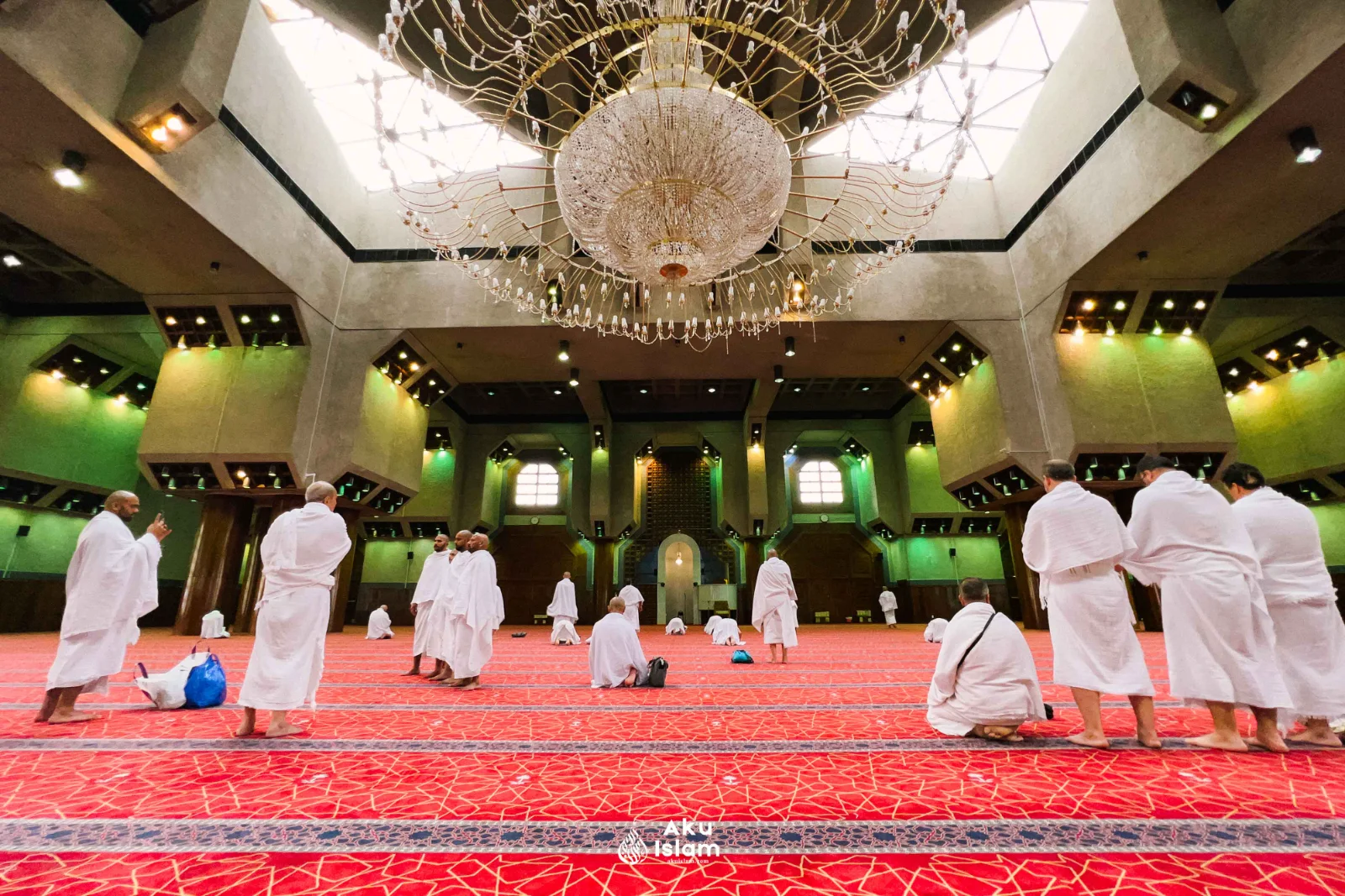 Jemaah berihram solat sunat di ruang solat Masjid Aisyah berkarpet merah dengan lampu gantung