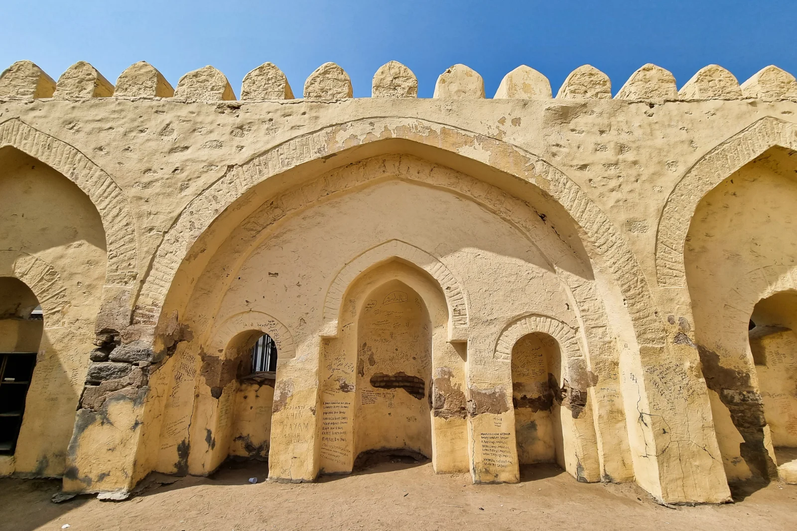 Gerbang melengkung dan mihrab Masjid al-Bai‘ah yang dibina dengan batu