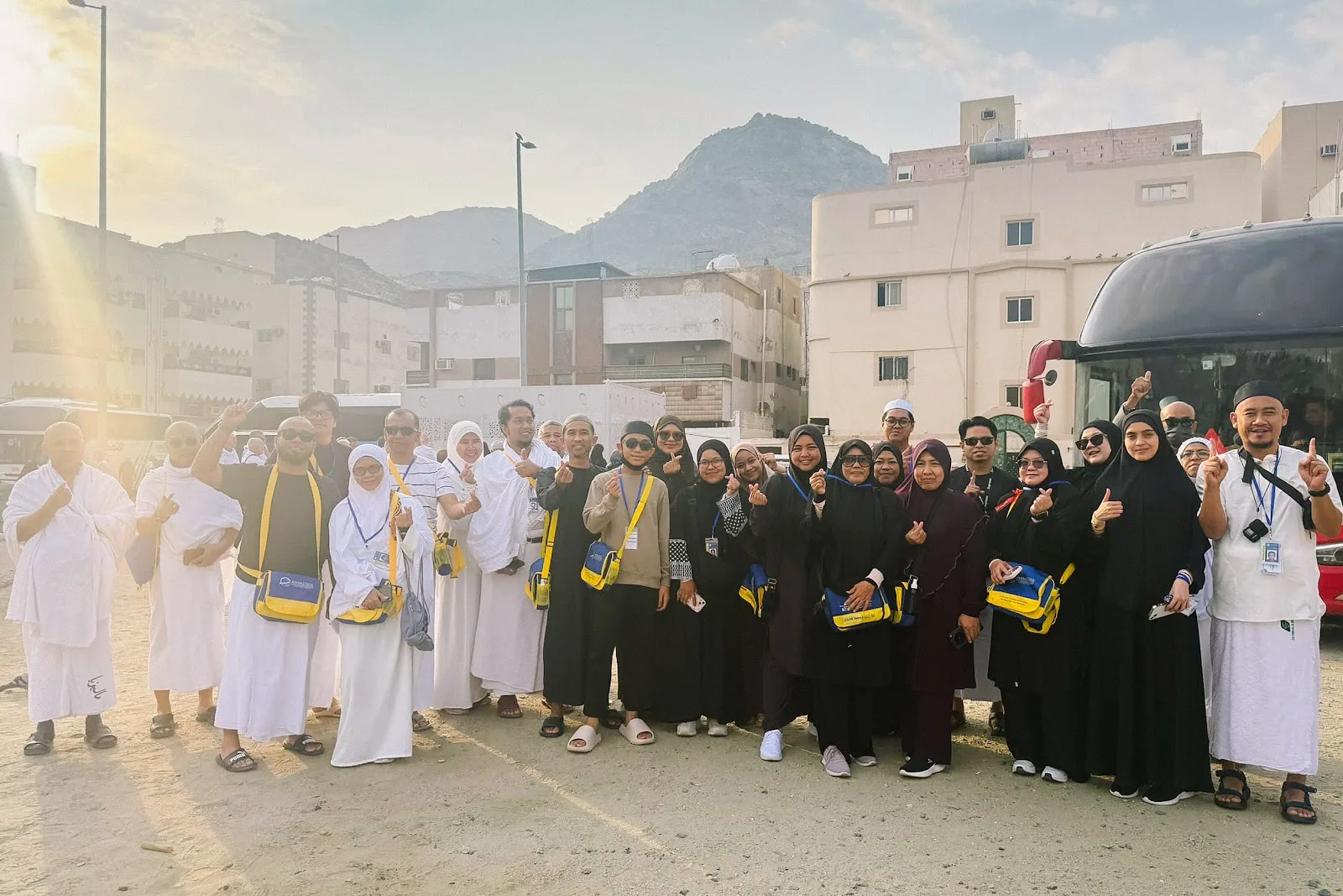 Rombongan jemaah lelaki dan wanita berpakaian ihram bersama bas di Makkah
