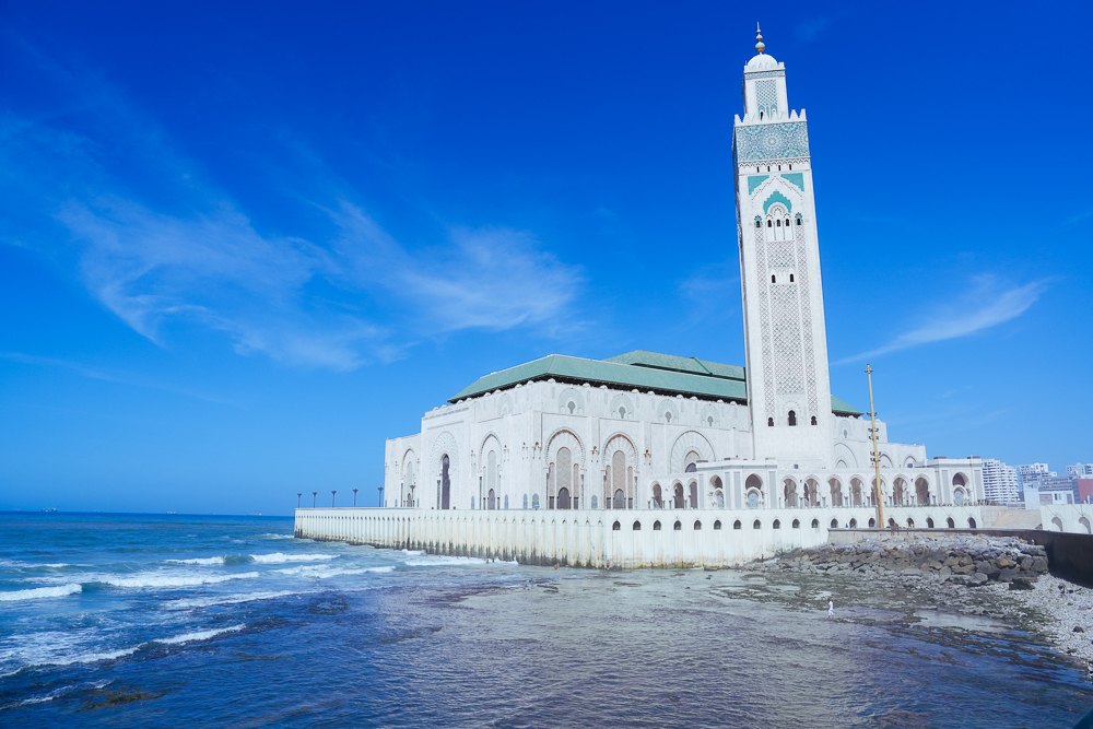 Menara Masjid Hassan II Casablanca di bawah langit biru dengan laut di hadapan