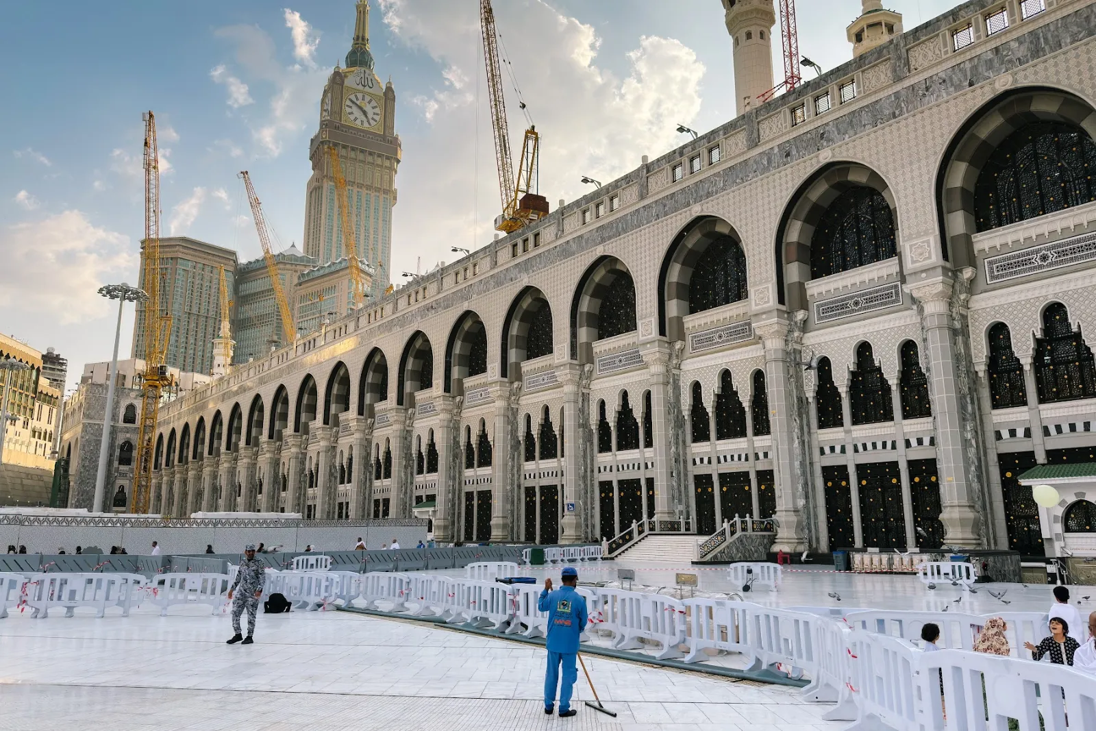 Serambi berlengkung Masjidil Haram dengan Menara Jam dan kren pembinaan di latar