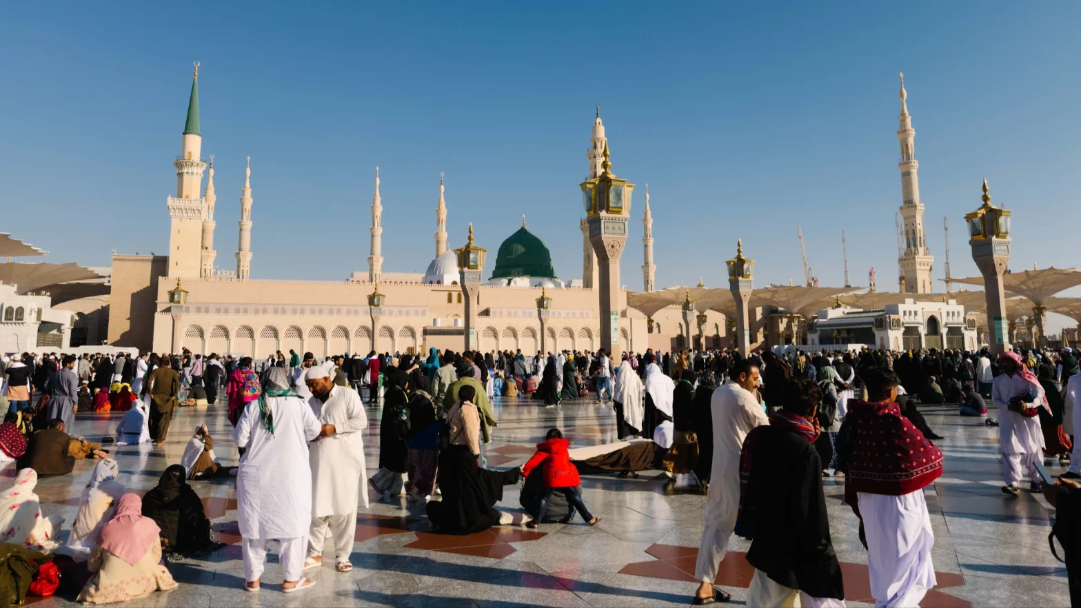 Jemaah di dataran Masjid Nabawi dengan Kubah Hijau dan menara pada waktu siang