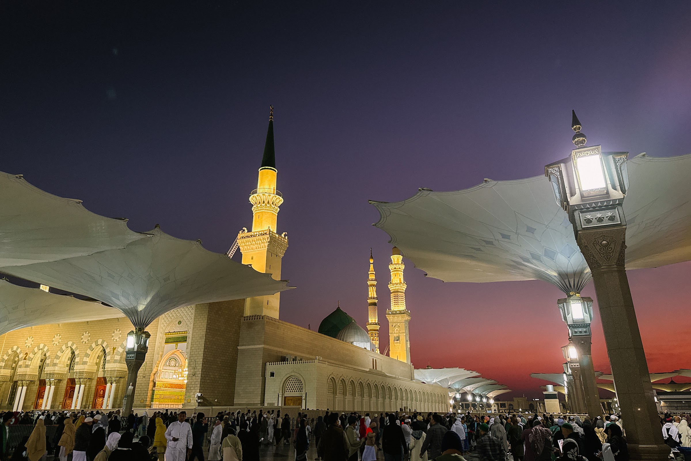 Masjid Nabawi dan Kubah Hijau pada waktu senja, dengan payung gergasi di perkarangan