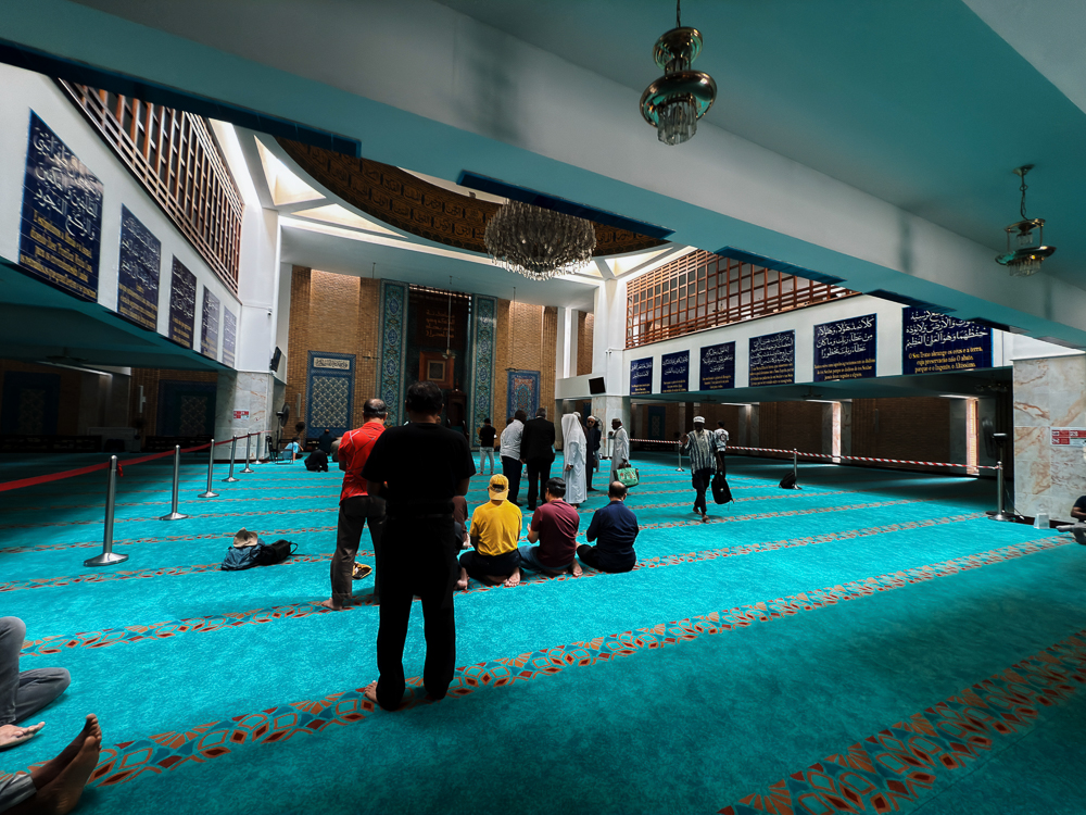 Dewan solat Masjid Pusat Lisbon dengan karpet biru dan jemaah