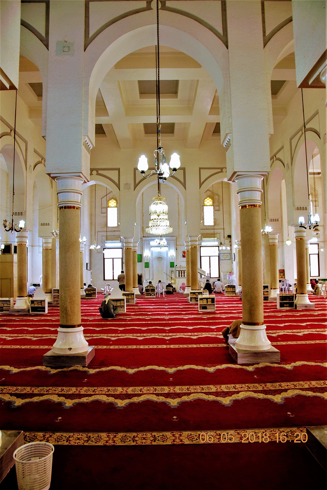 Ruang solat Masjid at-Taubah Tabuk dengan deretan tiang berlengkung, candelier dan karpet merah