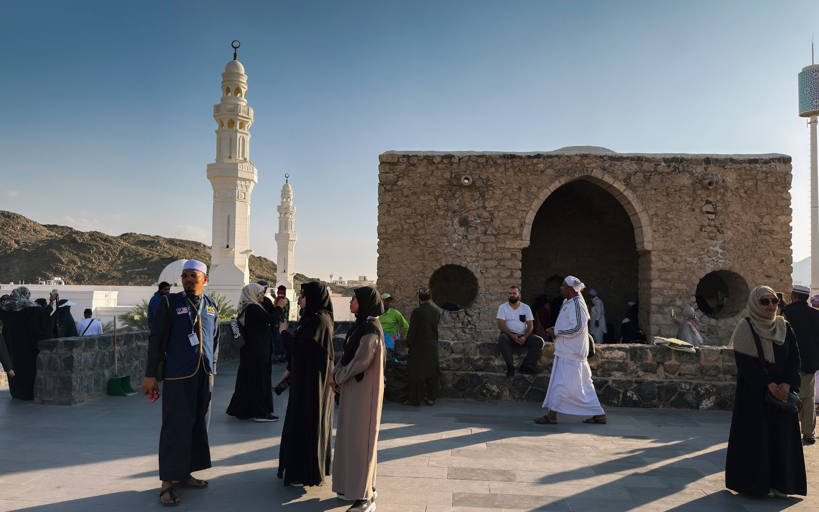 Jemaah umrah di hadapan masjid batu kecil kawasan Masjid Tujuh dengan menara Masjid Khandaq