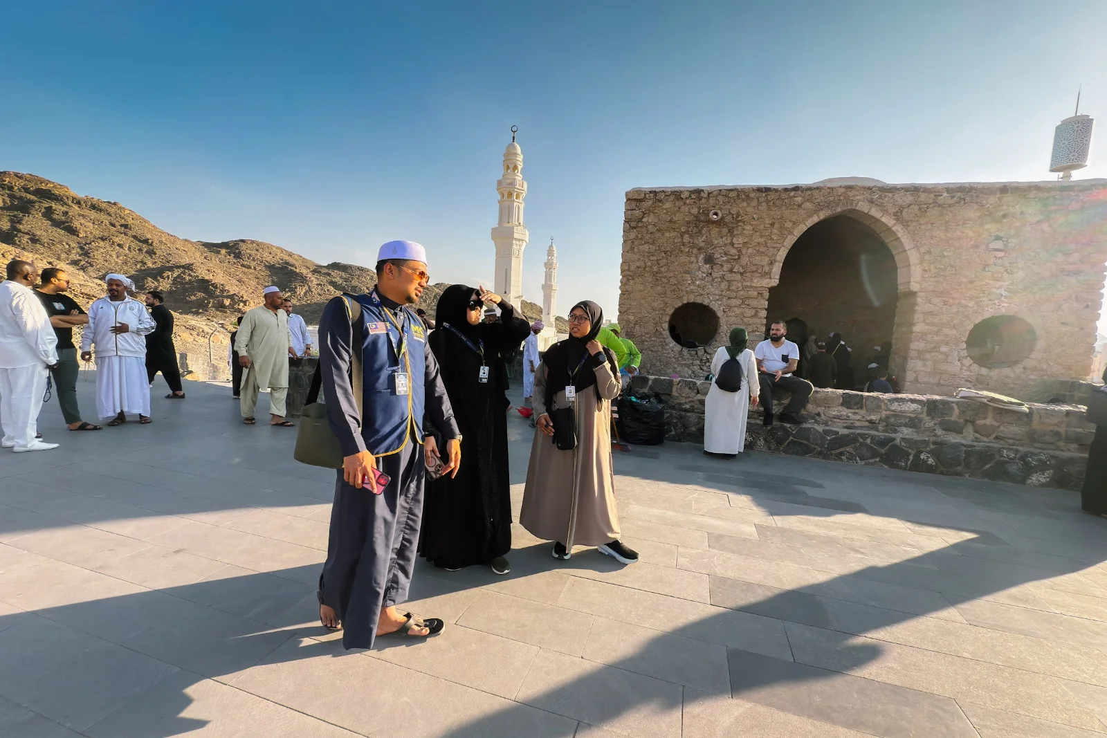 Mutawwif bersama jemaah umrah di dataran Masjid Tujuh dengan menara Masjid Khandaq dan Jabal Sala’