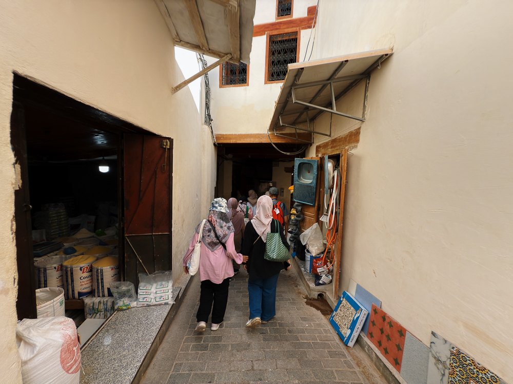 Peserta rombongan berjalan di lorong sempit medina Fez di antara kedai kecil
