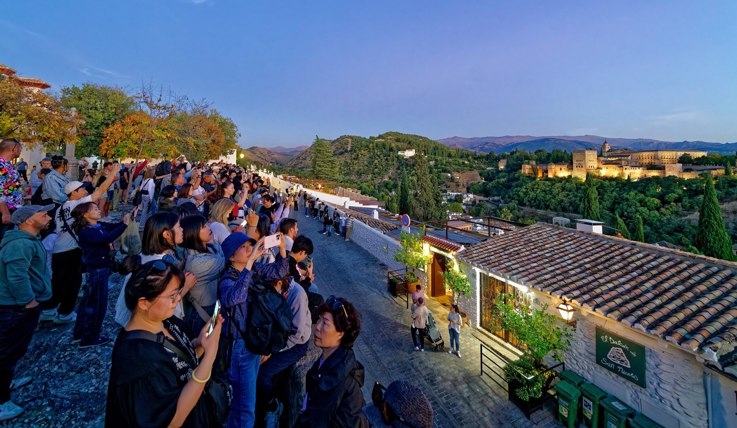 Pengunjung memenuhi Mirador de San Nicolás ketika senja menghadap Alhambra
