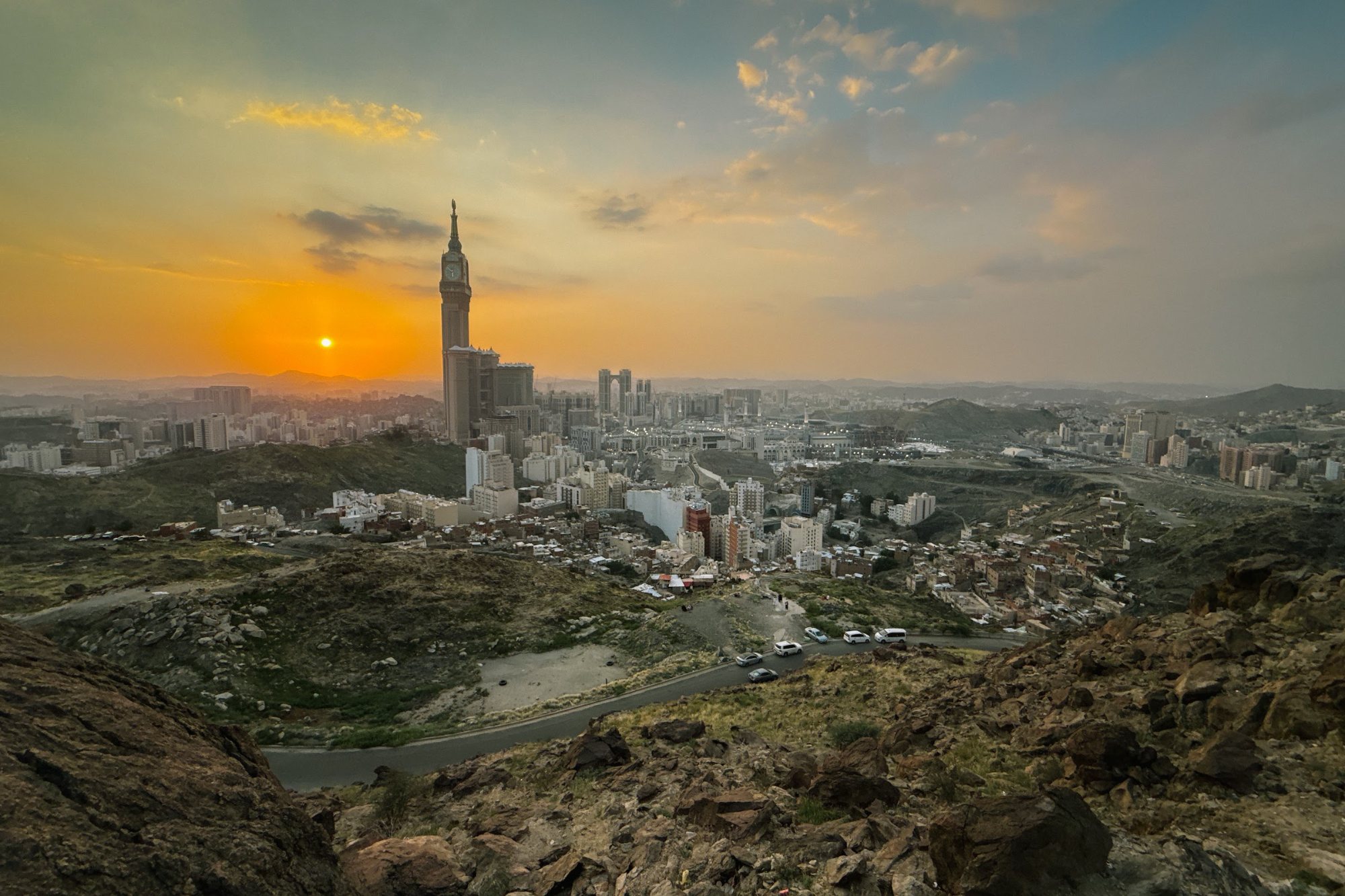 Langit senja di ufuk barat kota Makkah dilihat dari lereng Jabal Khandamah, dengan menara jam di kejauhan