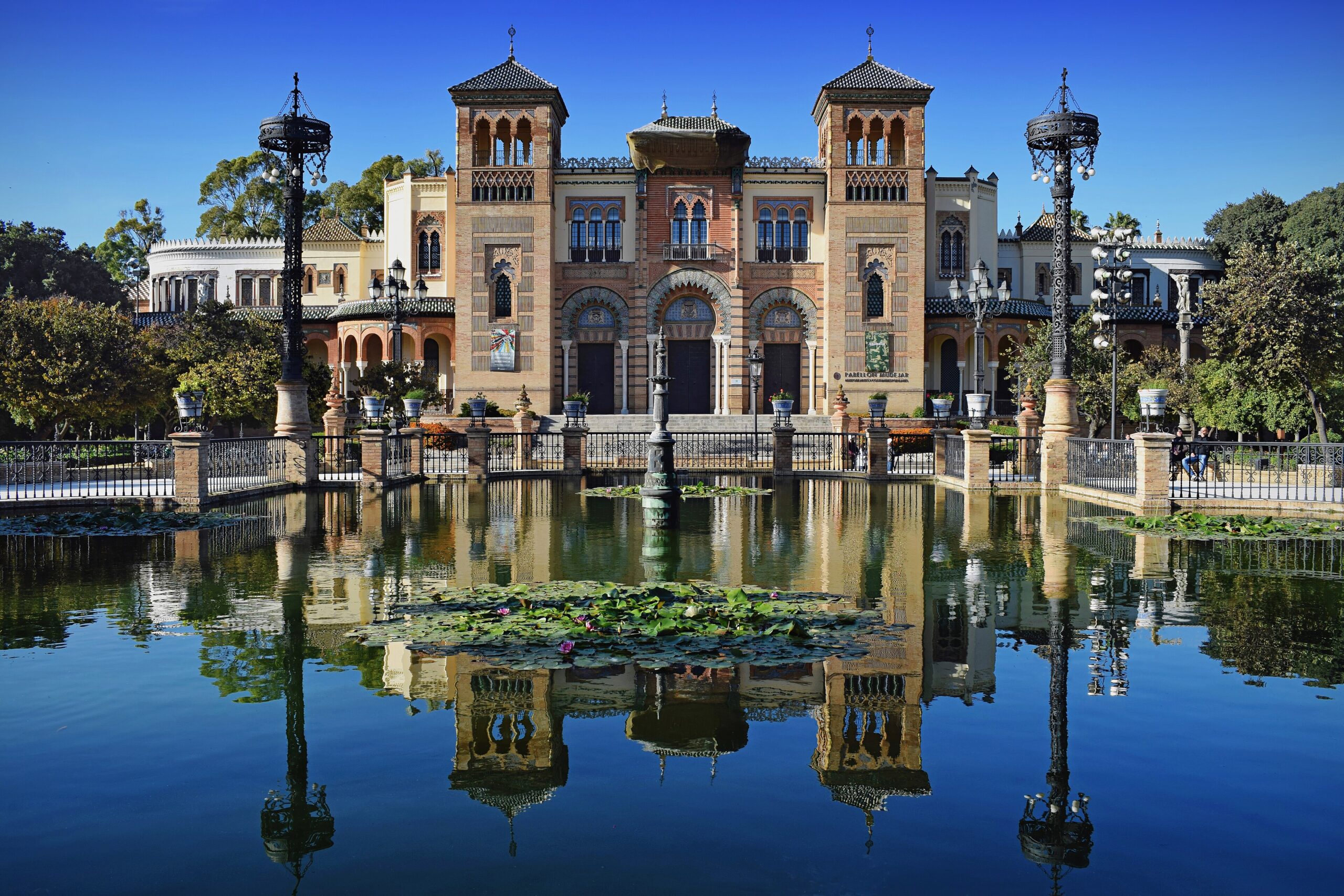 Pabellón Mudéjar di Plaza de America dengan pantulan di kolam, Taman María Luisa