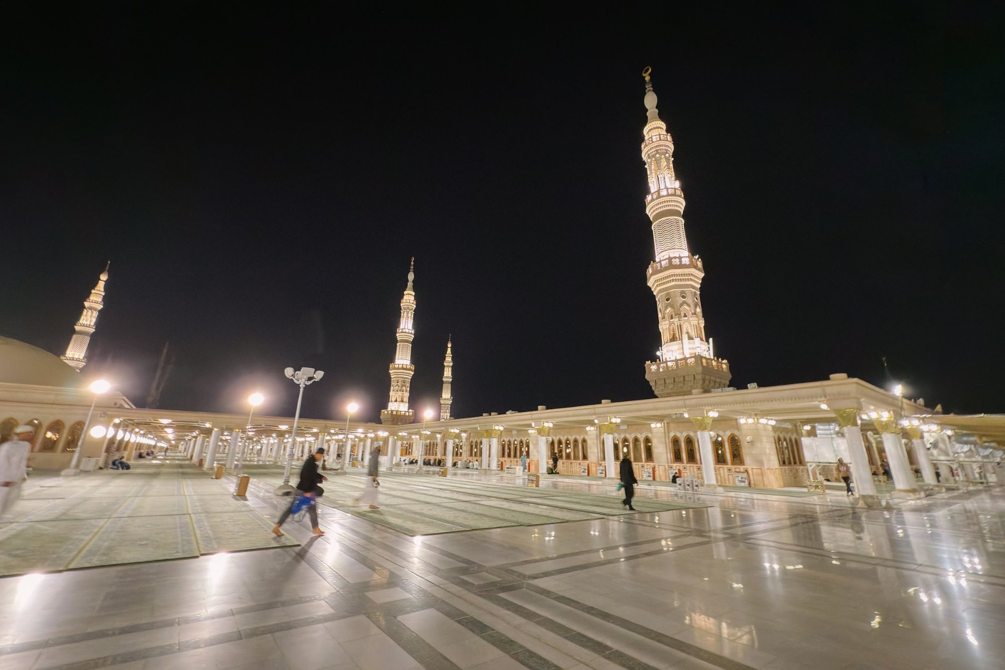 Menara Masjid Nabawi dan halaman masjid yang diterangi lampu pada waktu malam